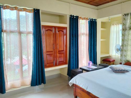 a bedroom with blue curtains and a bed and a window at Ribsweet Treetops Bed and Breakfast in Pynursla