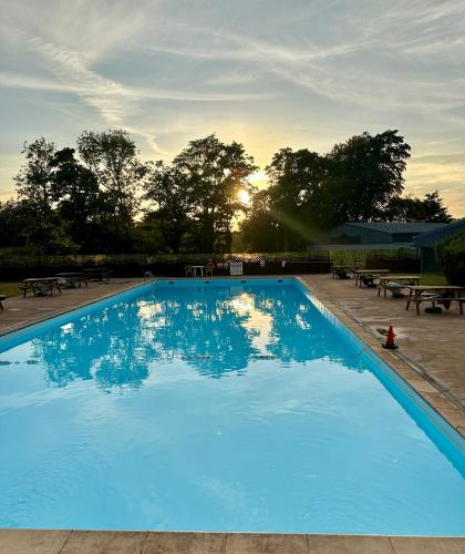 a large blue swimming pool with the sun setting at Swan lake lodge in Caernarfon