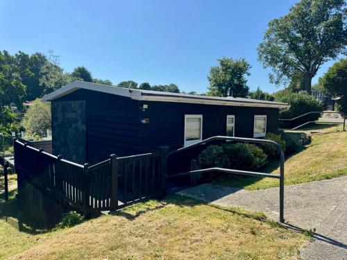 a small black tiny house with a gate at Swan lake lodge in Caernarfon