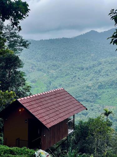 a small building with a red roof on a mountain at Paithal View Retreat in Paithalmala