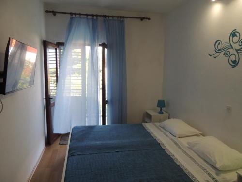 a bedroom with a bed with a blue blanket and a window at CROSurf Apartments Pelješac Kučište in Kučište