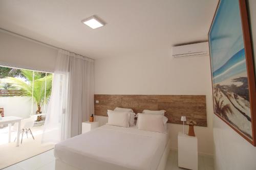 a white bedroom with a bed and a table at Pe na Areia Boutique Hotel in Japaratinga