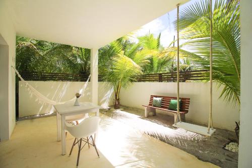 a room with a table and a swing and a bench at Pe na Areia Boutique Hotel in Japaratinga