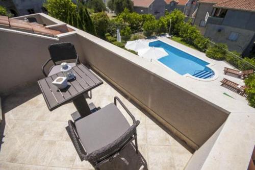 a patio with a table and chairs and a swimming pool at Župa Dubrovačka Guest House in Mlini