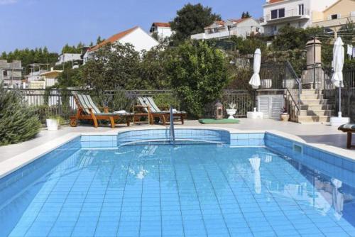 a large swimming pool with two chairs and a house at Župa Dubrovačka Guest House in Mlini