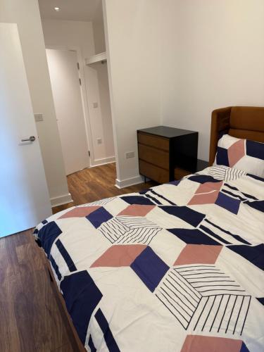a bedroom with a bed with a checkered blanket at AA Apartment in Barking