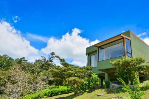 a green house on a hill with trees at Rainbow Valley Lodge Costa Rica in Monteverde Costa Rica