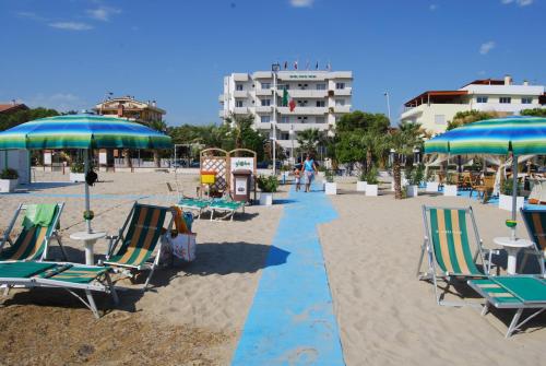 a beach with chairs and umbrellas and a building at Hotel Costa Verde in Tortoreto Lido