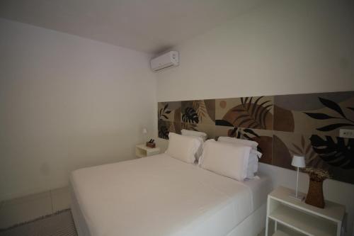 a white bed with two pillows in a room at Pe na Areia Boutique Hotel in Japaratinga