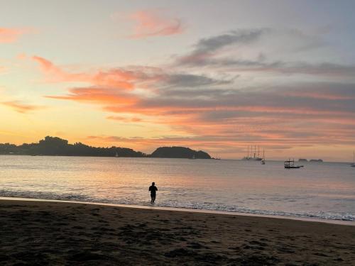 a person standing on the beach at sunset at Beachy Studio Hideaway Steps to Sand & Sunset in Playa Flamingo