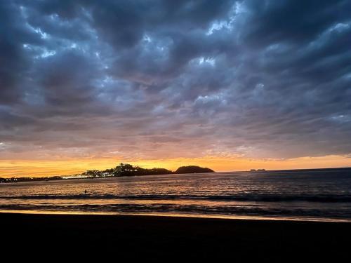 a beach with a cloudy sky and the ocean at Beachy Studio Hideaway Steps to Sand & Sunset in Playa Flamingo