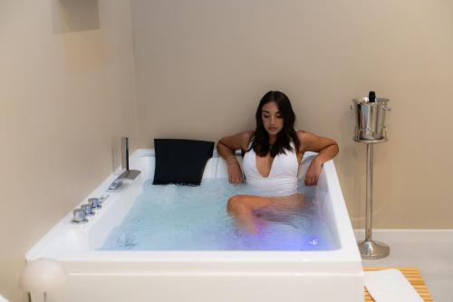 a woman is sitting in a bath tub at 5 Stars - Exclusive Luxury Suites with a jacuzzi in Trapani