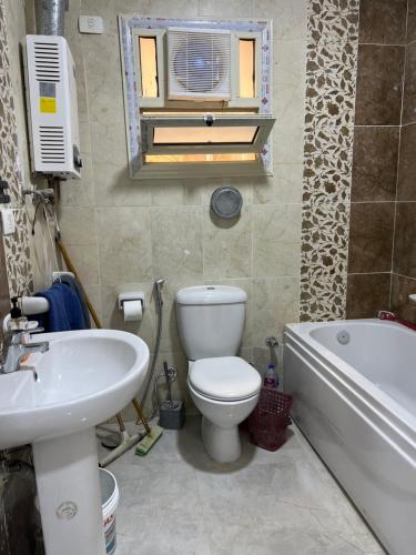 a bathroom with a toilet and a sink and a tub at Garden view 3 BR 2 balconies in compound in Obour