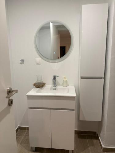a white bathroom with a sink and a mirror at Nikis Hοuse in Elia Laconias