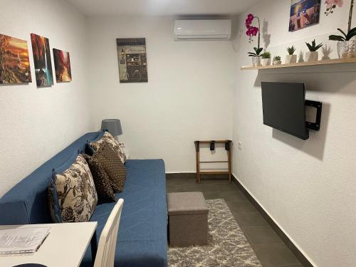 ein Wohnzimmer mit einer blauen Couch und einem Fernseher in der Unterkunft Sutomore Panorama Apartment in Sutomore