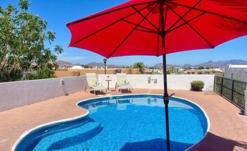 a red umbrella sitting next to a swimming pool at Casa Llena de Vida LB8 Alberca privada VISTA A LA BAHIA in San Carlos