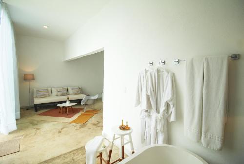 a white bathroom with a toilet and a room at Pe na Areia Boutique Hotel in Japaratinga