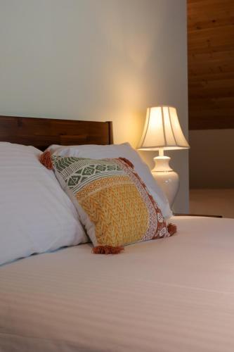 a bed with a pillow on it with a lamp at Custom Built Home on the Beach in Nelson