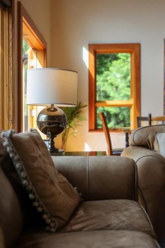 a living room with a brown couch and a lamp at Custom Built Home on the Beach in Nelson