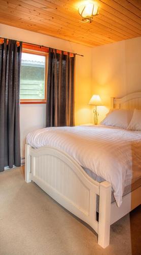 a bedroom with a white bed with a window at Custom Built Home on the Beach in Nelson