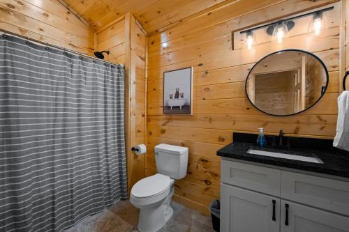 ein Badezimmer mit Toilette, Waschbecken und Spiegel in der Unterkunft Relaxing cabin retreat-pool, hot tub and game room in Sevierville