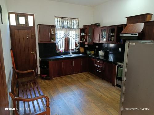 a kitchen with wooden cabinets and a wooden floor at Templewood villa in Nittambuwa