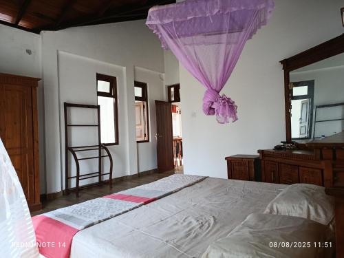 a bedroom with a bed with a purple mosquito net at Templewood villa in Nittambuwa