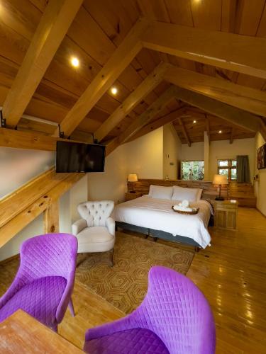 a bedroom with a bed and two purple chairs at Hotel Quinta los Morales in San Cristóbal de Las Casas