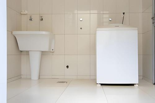 a white bathroom with a toilet and a sink at Casa com piscina no Botânico in Ribeirão Preto