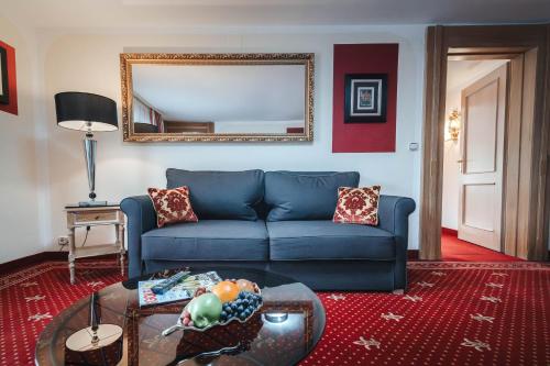 a living room with a blue couch and a mirror at Alpin & Wellness Resort Ludwig Royal in Oberstaufen