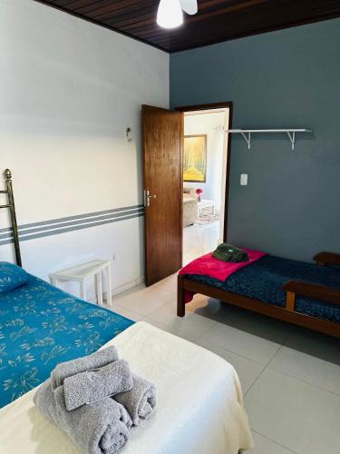 a bedroom with two beds and a door to a bathroom at Geribá - casa plana, conforto, adaptada e tudo a pé in Búzios