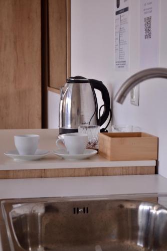 a tea kettle and two cups on a kitchen counter at Veluxe Stays in Kosovo Polje