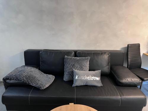 a black leather couch with two pillows on it at Moderne City Wohnung Paderborn Zentrum in Paderborn