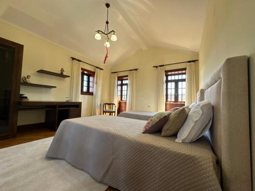 a bedroom with a bed and a desk and windows at Quinta dos Silvas in Santa Maria da Feira