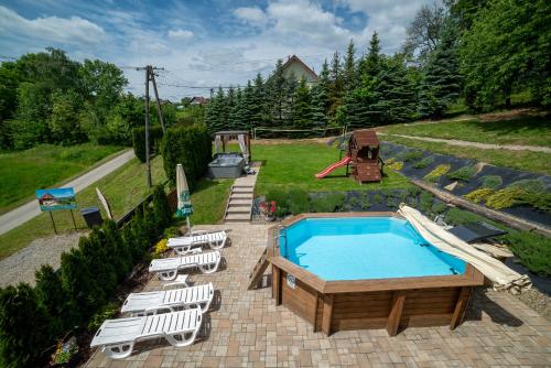 a swimming pool with lounge chairs and a playground at Willa Sulimówka - Noclegi Zakliczyn dom basen bania sauna SPA in Zakliczyn