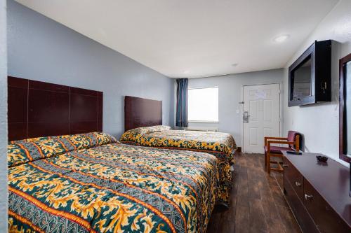 a hotel room with two beds and a desk at Hotel O Luxury Inn Channelview Baytown I-10 in Channelview
