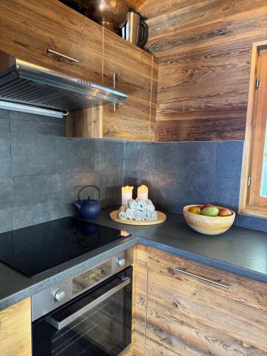 a kitchen with a stove and a bowl of fruit at Chalet Toccata, cosy et lumineux in Les Diablerets