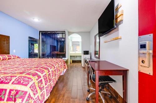 a hotel room with a bed and a desk and a tv at Hotel O Luxury Inn Channelview Baytown I-10 in Channelview