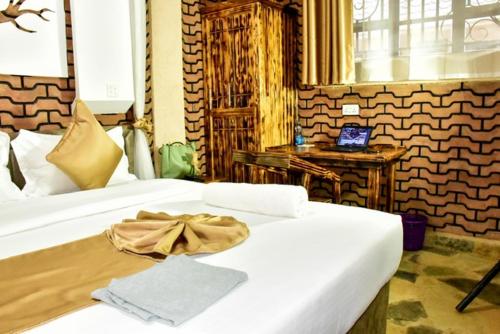 Un dormitorio con dos camas blancas con un lazo sobre ellas. en Mawimbi Jiko Hotel, en Taveta