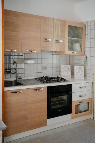 a kitchen with wooden cabinets and a stove top oven at Casa Sole - Villetta al mare, patio e relax in Carrao