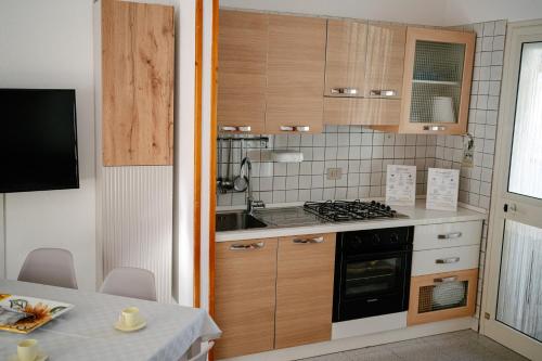 a kitchen with wooden cabinets and a stove top oven at Casa Sole - Villetta al mare, patio e relax in Carrao