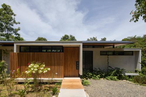 a home with a wooden door and a garden at Sinfonía Tropical, ocean view, 5 minutes driving to Playa Linda, 15 to Dominical, wifi Starlink in Savegre
