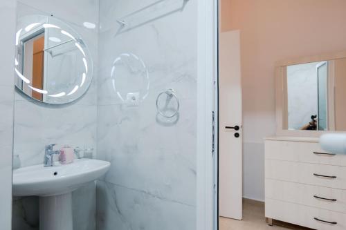 a white bathroom with a sink and a mirror at Modern Central Apartments Saranda in Sarandë