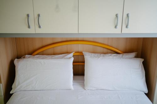 a bed with white pillows and cabinets above it at Casa Sole - Villetta al mare, patio e relax in Carrao