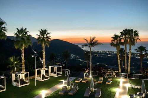 a view of a hotel with palm trees and lights at The Noverian Scenic Crete 5 Star Hilltop Villa Resort & Spa in Malia