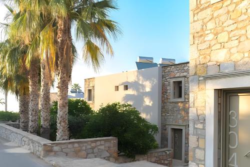 a building with palm trees in front of it at The Noverian Scenic Crete 5 Star Hilltop Villa Resort & Spa in Malia