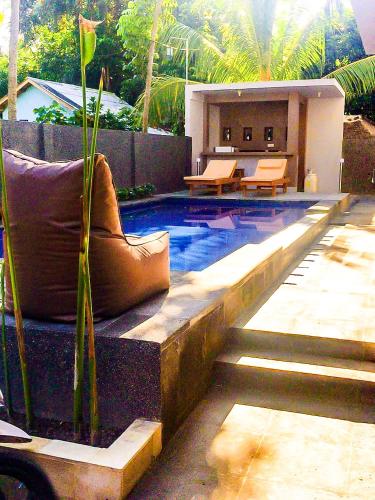 a swimming pool with a bench and a table at Lazy Inn Kuta Lombok in Kuta Lombok