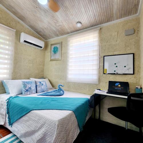 a bedroom with a bed and a desk with a laptop at CoralStone Escape near beach and airport with private garden in Christ Church