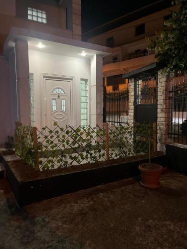 a white front door of a house with a fence at Vila Nikollaj in Kamëz