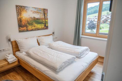 a bed with white sheets in a room with a window at Triebenstein Hideaway in Hohentauern